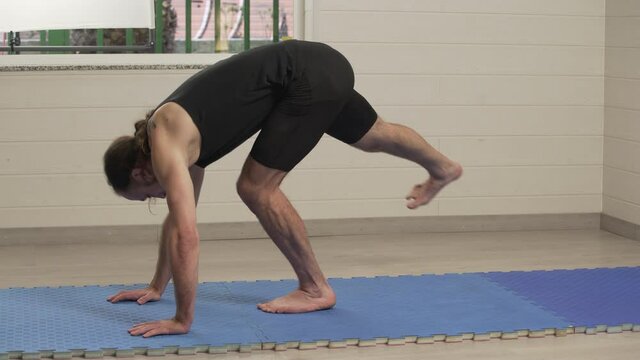 Fit male stretching his leg to improve flexibility. Bodyweight training at home
