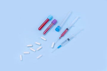 blood vials, syringes, medical capsules on a blue background.