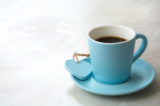a cup of coffee with a heart on a light blurred table background