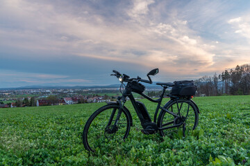 Fototapeta na wymiar Black and gray electric bicycle in sunset time with cloudy sky