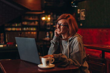 Young redhead woman using a laptop in a cafe