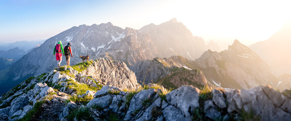 two hikers with dog in the mountains