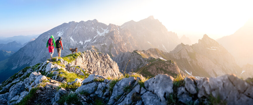 two hikers with dog in the mountains