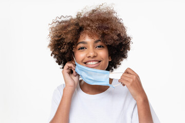 Smiling african american school girl taking off face mask after the end of pandemic. Concept of...