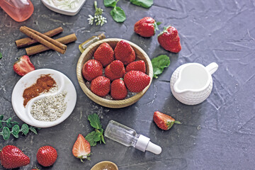 Ingredients homemade strawberry face mask, cream, strawberry, oatmeal, spices, herbs on a dark background, top view, copy space, flat lay/ Home hand-made cosmetics made from natural ingredient
