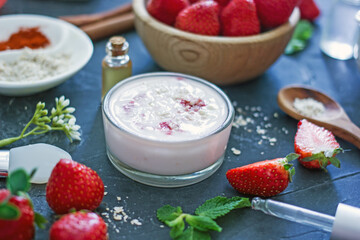 Homemade strawberry face mask with oatmeal and cream on a dark background. Concept of natural...
