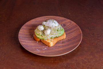 Brown toast plate with avocado and poached chicken egg and cooked quail eggs