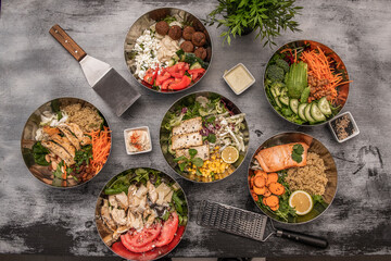 set of metal bowls filled with poke, salads, quinoa and all kinds of healthy food