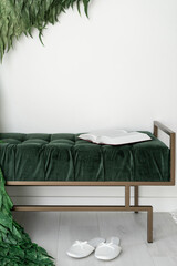 Book on green velour bench against white wall