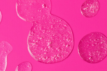 Round drops of white gel with bubbly texture.Jelly texture of antibacterial liquid with bubbles iside.Bright pink background with copy space,advert banner,cosmetics concept.