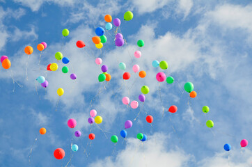 Lots of colorful balloons flying against blue sky with clouds with copy space. Concept of holiday, festival, Children's Day, Last call at school and kindergarten, birthday.