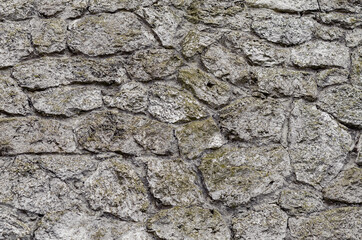 Stone wall made of gray natural untreated stone. Ancient medieval castle