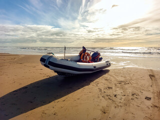 Rigid hull inflatable boat with outboard motor in the shore beaten by the waves. Used to fish at sea