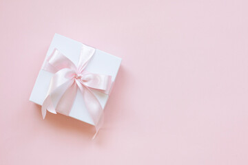 A gift box with pink ribbon on a pink background. Gift box background.