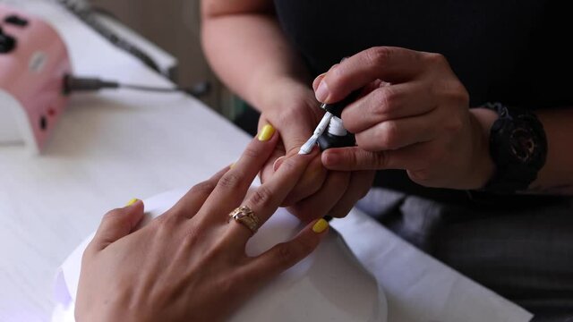 Anonymous ethnic doing manicure to client and applying nail polish