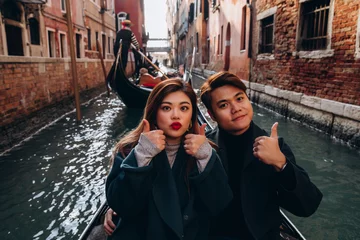 Foto op Plexiglas Een romantische rit voor een jongen en een meisje op een gondel door de grachten van Venetië. Een jong stel reist naar Italië. © dimadasha