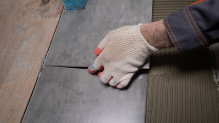 Laying ceramic tiles on the floor. Ceramic tile. The tiler is laying ceramic wall tiles on top of the adhesive. A worker smears ceramic tiles for laying.