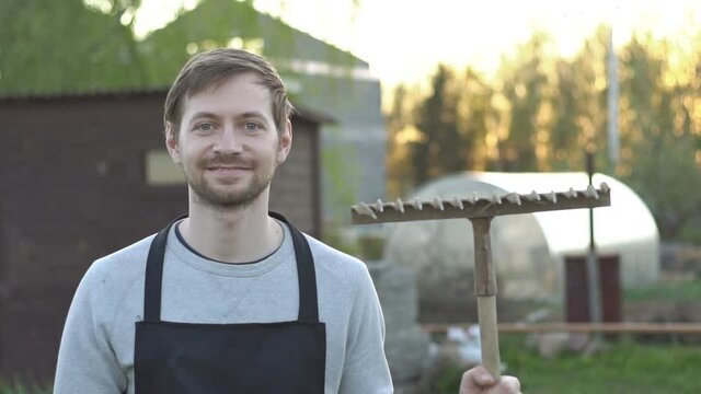 Portrait of male farmer with rake standing proud on his field and satisfied smiling