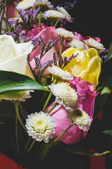 Spring bouquet of bright multi-colored flowers close-up. Bouquet of roses, tulips in green leaves.