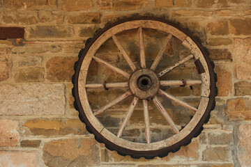 A vintage cart wheel on an old stone wall