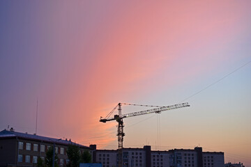 Tower crane in the city on the background of a beautiful sunset sky