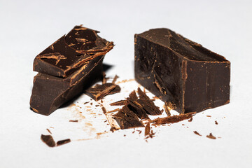 Dark chocolate split in half with little pieces and shavings on white background