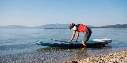 Young man going on a sup to paddle