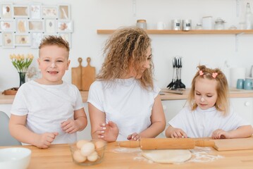 happy family in the kitchen. mother and children preparing the dough, bake cookies