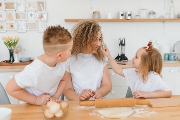 An attractive smiling family of mother, and two children, boy, girl, son, daughter cookies in a kitchen at home