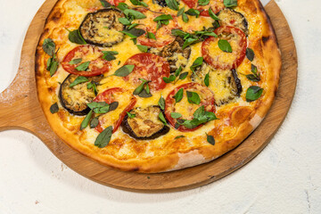 Veggie Vegan Pizza with Aubergine Basil and Cheese on A Rustic Tomato Sauce Homemade Artesanale Close Up Detail on a Round Wooden Plate with Flour Background Table