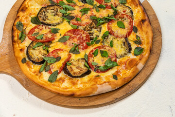 Veggie Vegan Pizza with Aubergine Basil and Cheese on A Rustic Tomato Sauce Homemade Artesanale Close Up Detail on a Round Wooden Plate with Flour Background Table