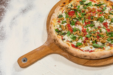 Ricotta Cheese Pizza with Basil and Nuts on a Rustic Tomato Sauce Homemade Artesanale Close Up Detail on a Round Wooden Plate with Flour Background Table