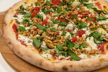 Ricotta Cheese Pizza with Basil and Nuts on a Rustic Tomato Sauce Homemade Artesanale Close Up Detail on a Round Wooden Plate with Flour Background Table