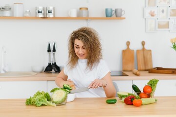 Woman making salad in kitchen. Healthy eating lifestyle concept with beautiful young woman cooking in her kitchen.