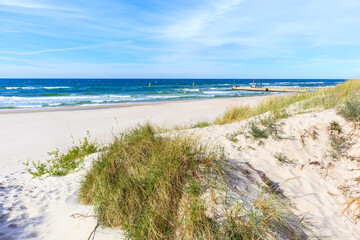 Sand dunes and view of beautiful beach in Dzwirzyno village near Kolobrzeg town and sunny blue sky, Baltic Sea coast, Poland