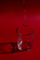 Glass of water with red background