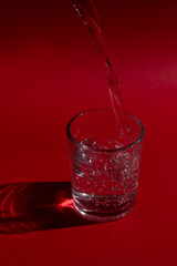 Glass of water with red background