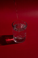 Glass of water with red background