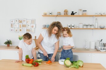Young mother and her two kids making vegetable salad