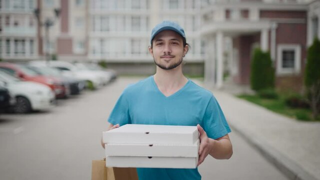 A young and energetic delivery man, carrying a pizza and a bag of groceries. The man is doing his job.