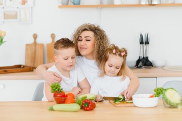 Obraz na płótnie Canvas mother with children preparing vegetable salad at home