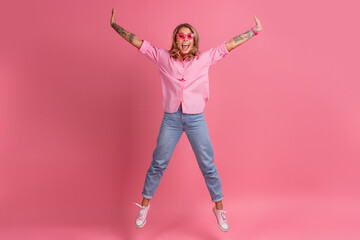 Fototapeta na wymiar blond pretty woman in pink shirt and jeans smiling jumping