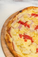 Loin and Pineapple Pizza with Mango Chutney Tropical Sauce Homemade Artesanale Close Up Detail on a Round Wooden Plate with Flour Background Table