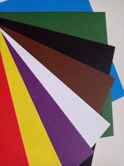 Colored paper spread out in a fan.Background. Red, Yellow, Purple, White, Blue, Brown, Green, Brown