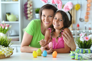  Mother with daughter wearing rabbit ears decorating  Easter eggs at home