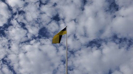 Ukrainian flag waves in wind on cloudscape background at sunny day. Yellow and blue flag of Ukraine country. Fluffy white cumulus clouds in blue sky