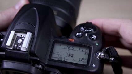 Male photographer adjusts settings on DSLR camera close up