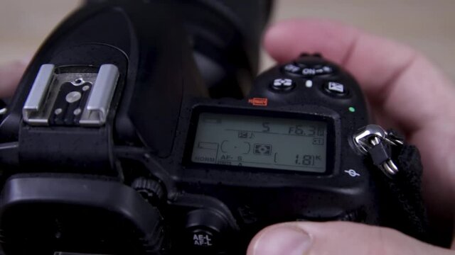 Male photographer adjusts settings on DSLR camera close up