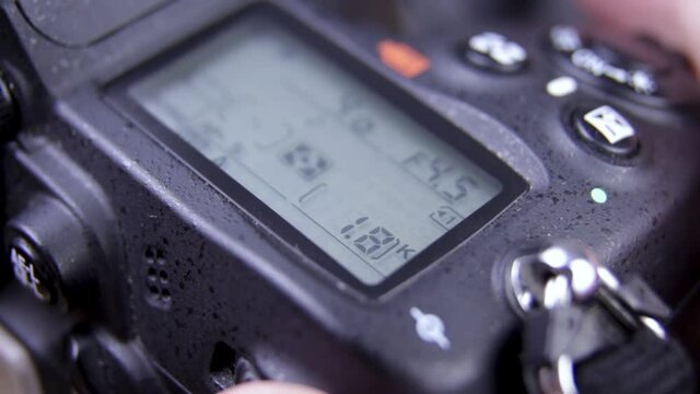 Photographer holding DSLR camera adjusting settings - close up