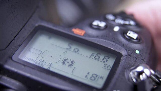 Photographer holding DSLR camera adjusting settings - close up